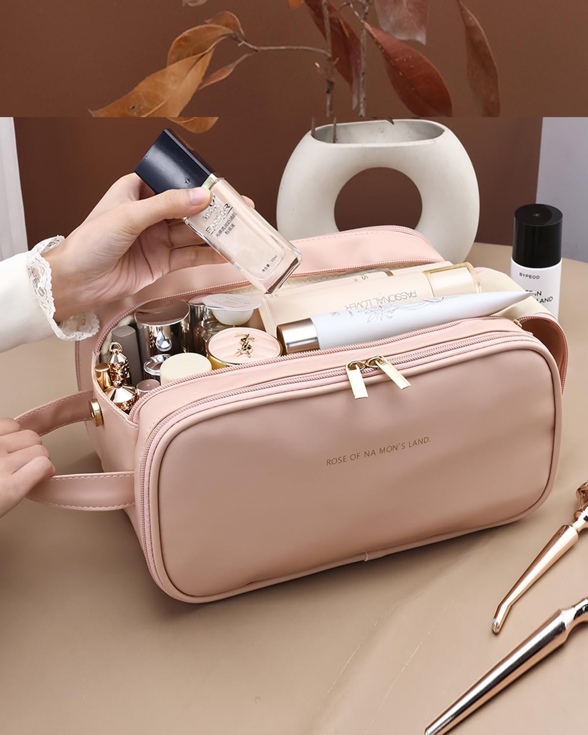 Pink travel makeup organizer bag with cosmetics being arranged inside