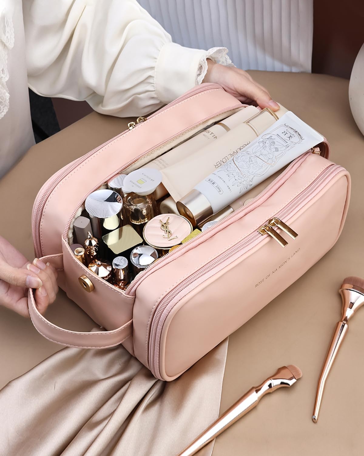 Pink makeup organizer bag open, showing cosmetics bottles and compact inside