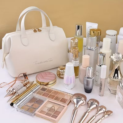 Cream beauty organizer bag with top zipper and handles, with makeup items around it